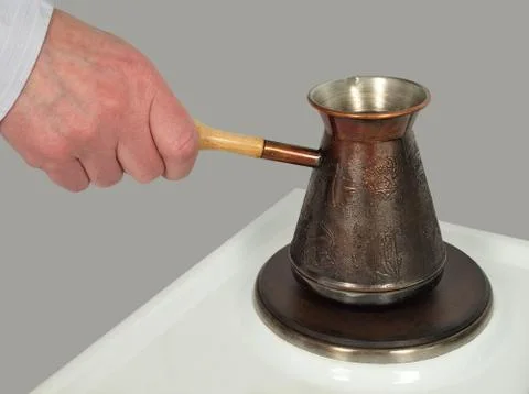 Hand holding an empty coffee on electric burner. Foto stock