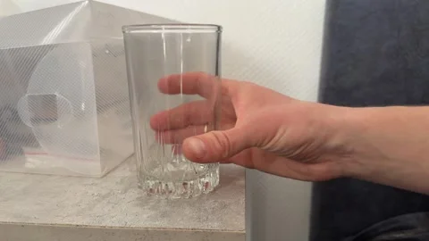 Hand holding empty drinking glass on kitchen counter Stock Footage 336976519