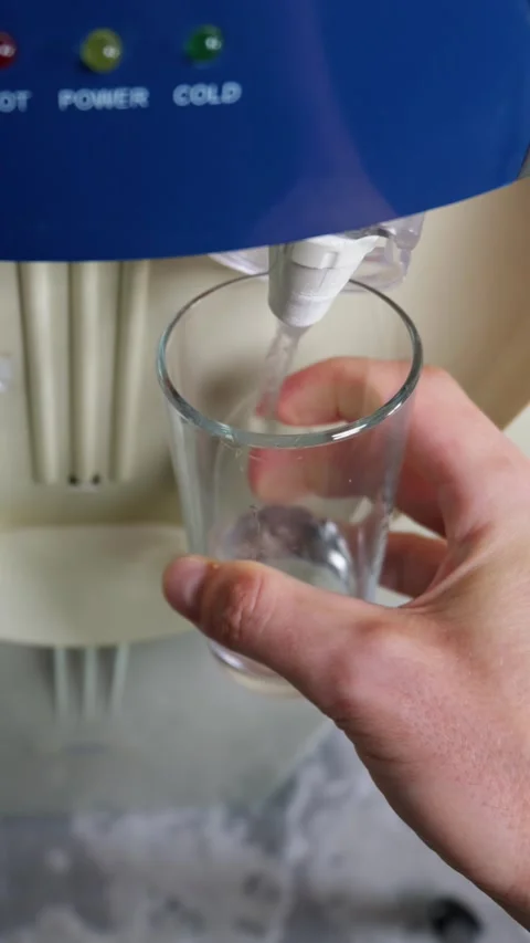 Hand Holding Empty Glass Under Blue Water Cooler Dispenser in Office Stock Footage 339207018