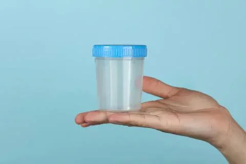 Hand holding empty plastic container with blue lid Stock Photos