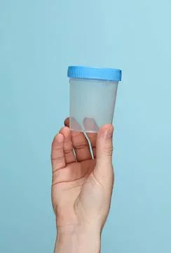 Hand holding empty plastic container with blue lid Stock Photos