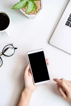 Hand holding empty screen Smart phone on business desk office with copy space Fotos Stock