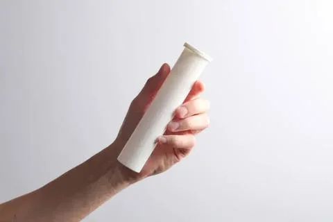 Hand holding empty white paper tube on plain background Photos