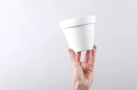Hand holding empty white plastic container against gray background Foto stock