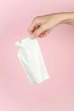 Hand holding empty white squeeze bottle on pink background Foto stock