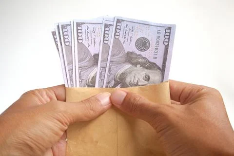 Hand holding an envelope containing 100 dollar bills on a white background Stock Photos