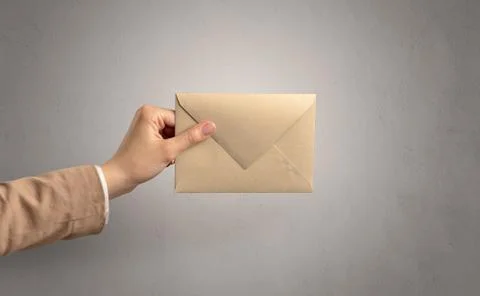 Hand holding envelope with empty wall background Stock Photos