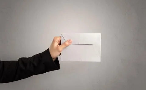 Hand holding envelope with empty wall background Stock Photos