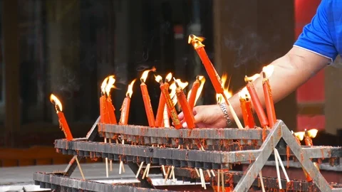 Hand holding flame from burning red chinese candle in the temple Video stock 114980935