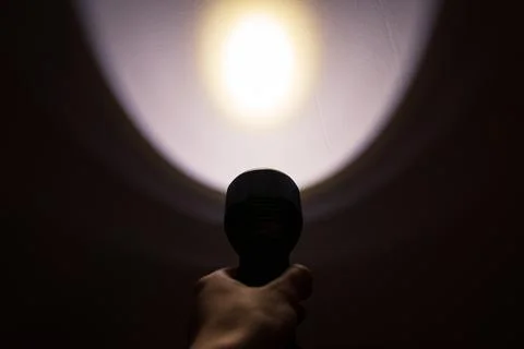 A hand holding a flashlight in the dark Stock Photos