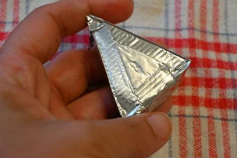 Hand holding a foil-wrapped processed cheese portion Stock Photos