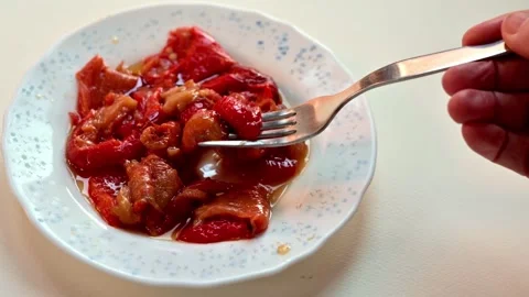 Hand holding fork eating roasted red peppers in olive oil plate images 스톡 동영상 327957428