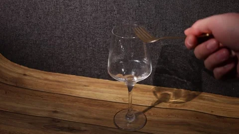 Hand holding fork near empty wine glass on wooden table with textured background Stock Footage 339181614