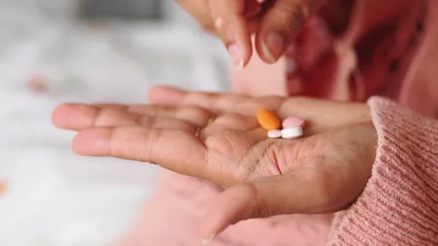 Hand holding four different pills in a home setting Stock Footage 340940138