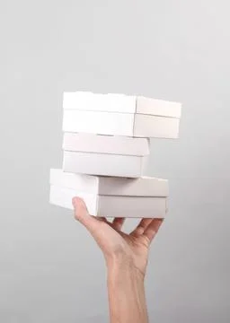 Hand holding four white boxes stacked in a row Stock Photos
