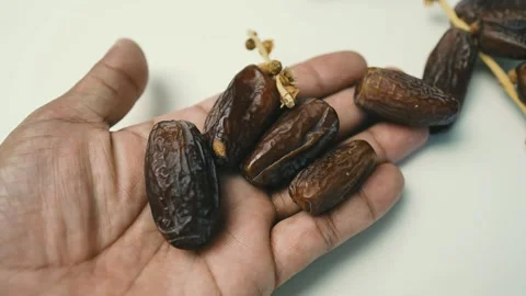 Hand Holding Fresh Dates, A hand holding several dates, with more dates att.. Stockbeeldmateriaal 304974797