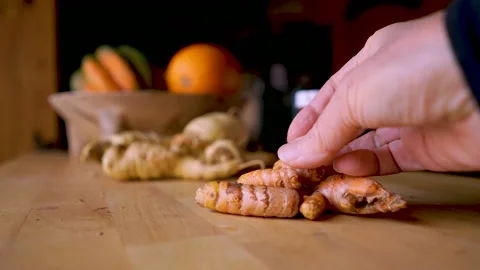 Hand holding fresh turmeric root with a prescription bottle in the background Stock Footage 145746793