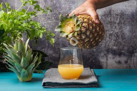 Hand holding a fruit, pineapple, which has a spout through which it pours t.. Stock Photos