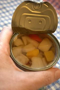 Hand holding fully opened fruit salad can Photos
