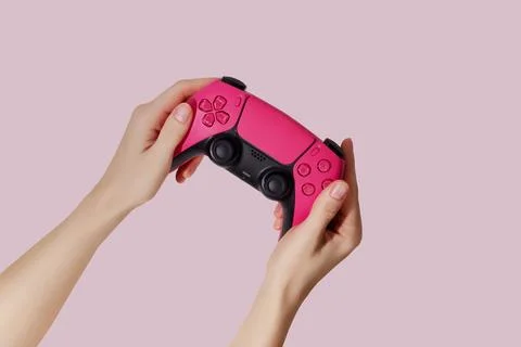 Hand holding a game controller on pink background Stock Photos