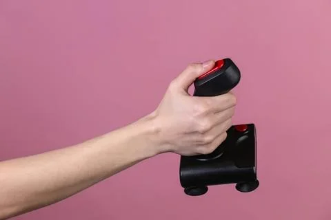 Hand holding game controller on pink background Stock Photos