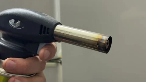 Hand holding gas torch lighter close up, portable flame tool for kitchen or Stock Footage 337120406