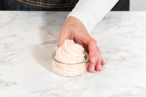 Hand holding glass bowl of peppermint buttercream Stock Photos