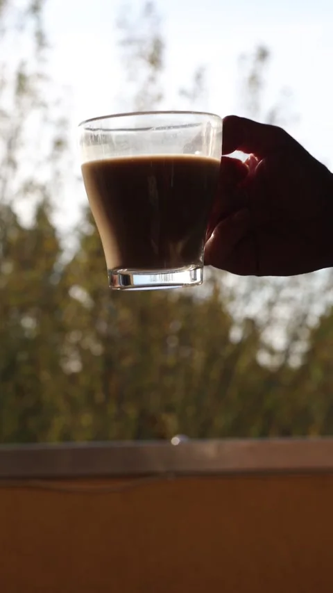 Hand holding a glass of coffee in backlight close up Stock Footage 346278281