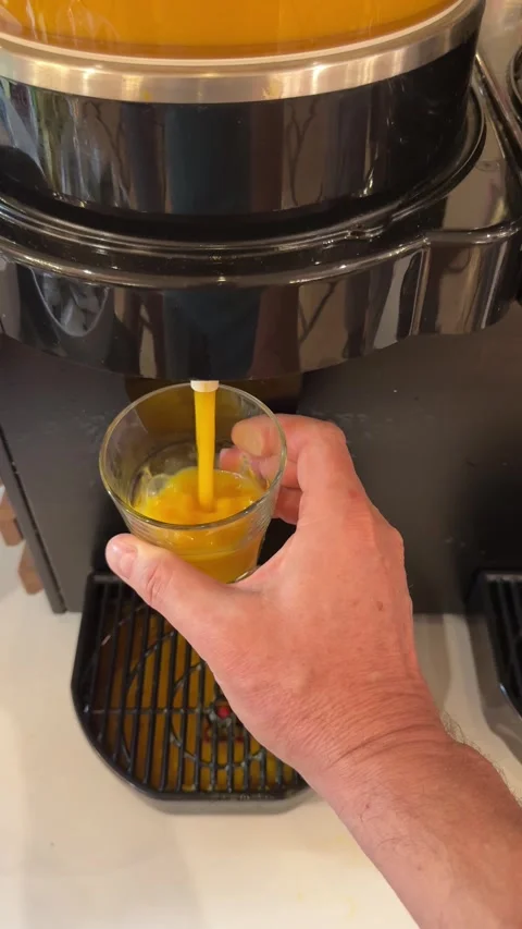 A hand holding a glass while pouring fresh orange juice into it, capturing a  動画素材 301852647