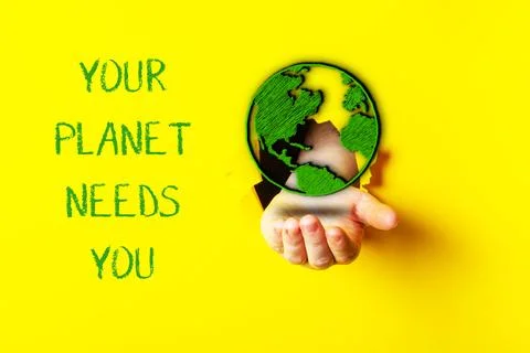 Hand holding a globe with the words Your planet needs you written below it Stock Photos