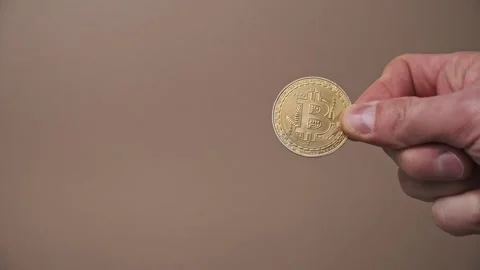 Hand Holding Gold Bitcoin on Solid Background Stock Footage 303833213