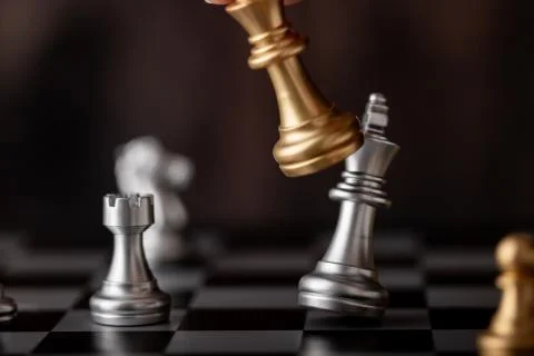 Hand holding gold king attack silver leader in game Foto stock