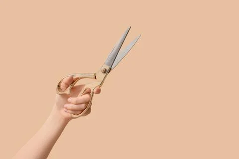 Hand holding gold tailor scissors with open blades, crafting and sewing tools Stock Photos