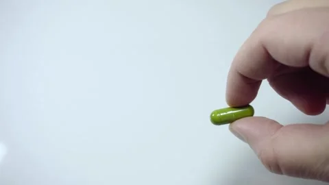 Hand holding green capsule pill close up isolated on white background Stock Footage 342838836