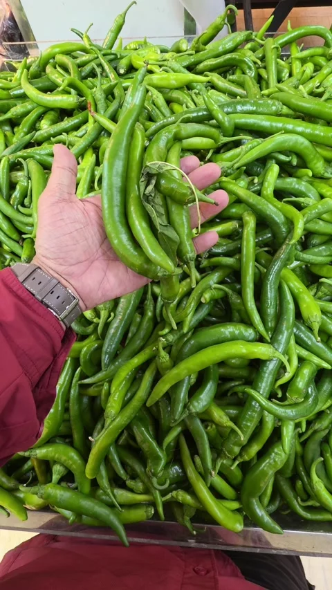 A hand holding green chillies while shopping in a supermarket Stock Footage 341554084