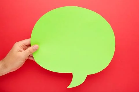 Hand holding an green empty speech bubble on red background Stock Photos