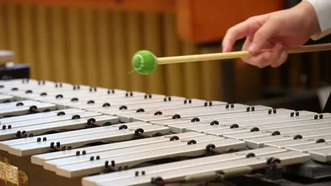 Hand holding green mallet over metal percussion bars. Stock Footage 339375982