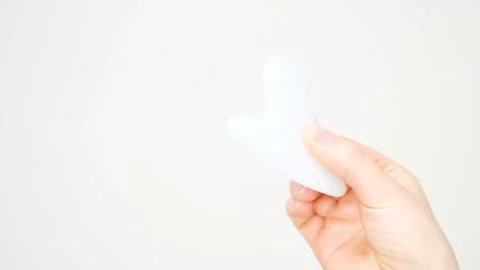 A hand holding gua sha face massager on white background. Stock Footage 329465073