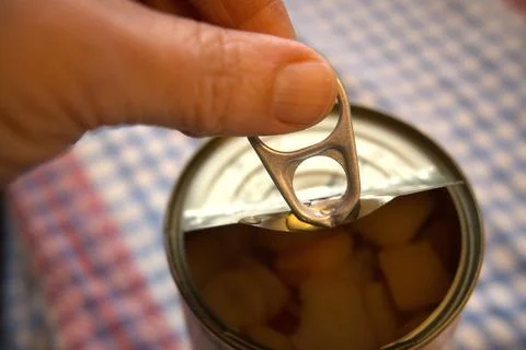 Hand holding half-open fruit salad can Fotos Stock