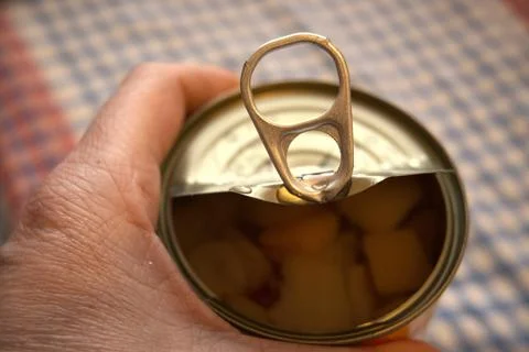 Hand holding half-open fruit salad can Fotos Stock