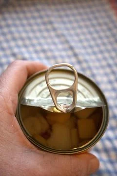 Hand holding half-open fruit salad can Фото