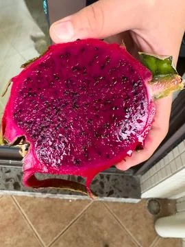 Hand holding half red pitaya dragon fruit showing seeds Stock Photos