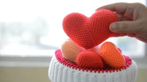 Hand holding heart made with a thread of a crocheted multicolored form hat. Vidéo 107656744