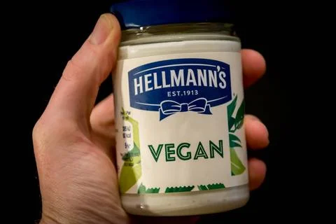  Hand holding Hellmann s Vegan and plant-based mayonnaise spread on black ... Stock-Fotos