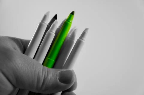 Hand holding highlighters but only green marker stands out Stock Photos