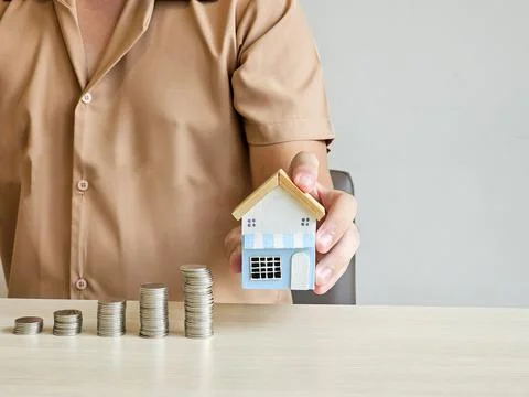 Hand holding house and stack of money coins, investment and savings concept Foto stock