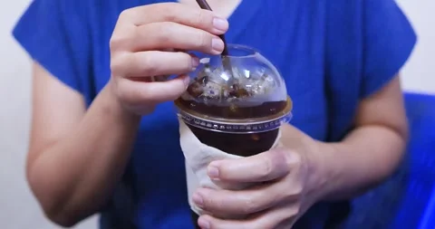 Hand holding an iced black coffee Americano in a plastic takeaway cup Stock Footage 338192190