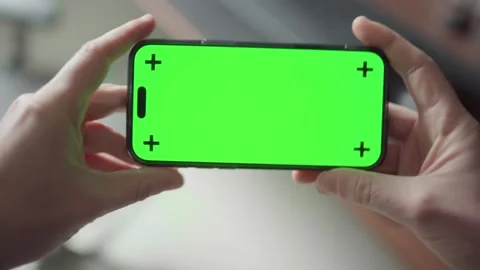 Hand holding iPhone 16 Pro Max with green screen, switching to landscape mode Stock Footage 295131682