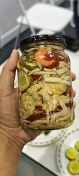 Hand holding a jar of assorted pickled vegetables Fotos Stock