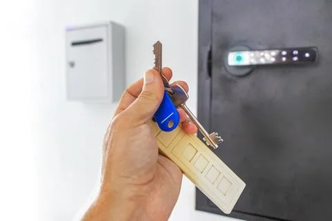 Hand holding keys from pin code box on hotel lobby wall Thailand. Foto stock